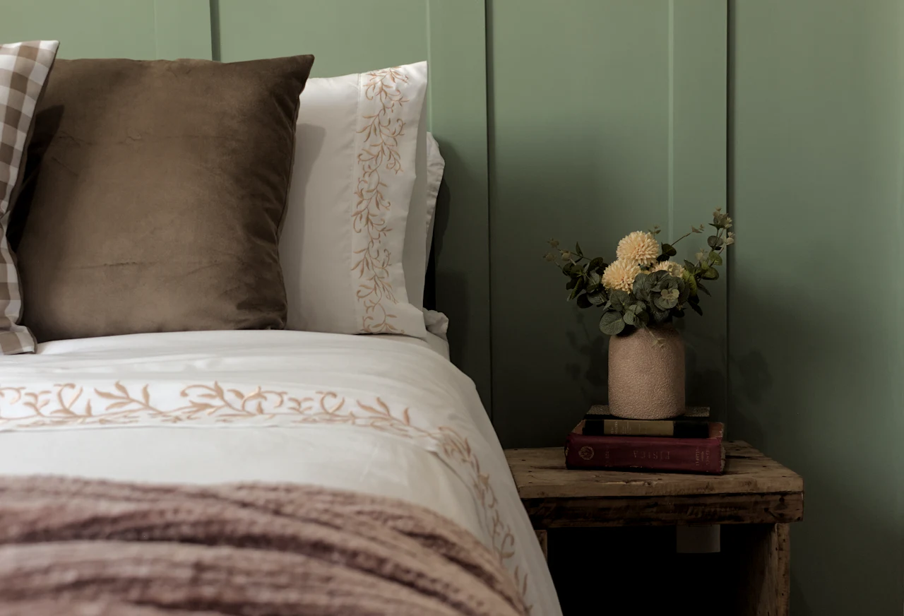 The Fell Room, with sage green panelling, white linen and a heather-coloured throw