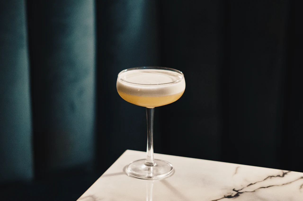 A cocktail in a glass on a dark bar table