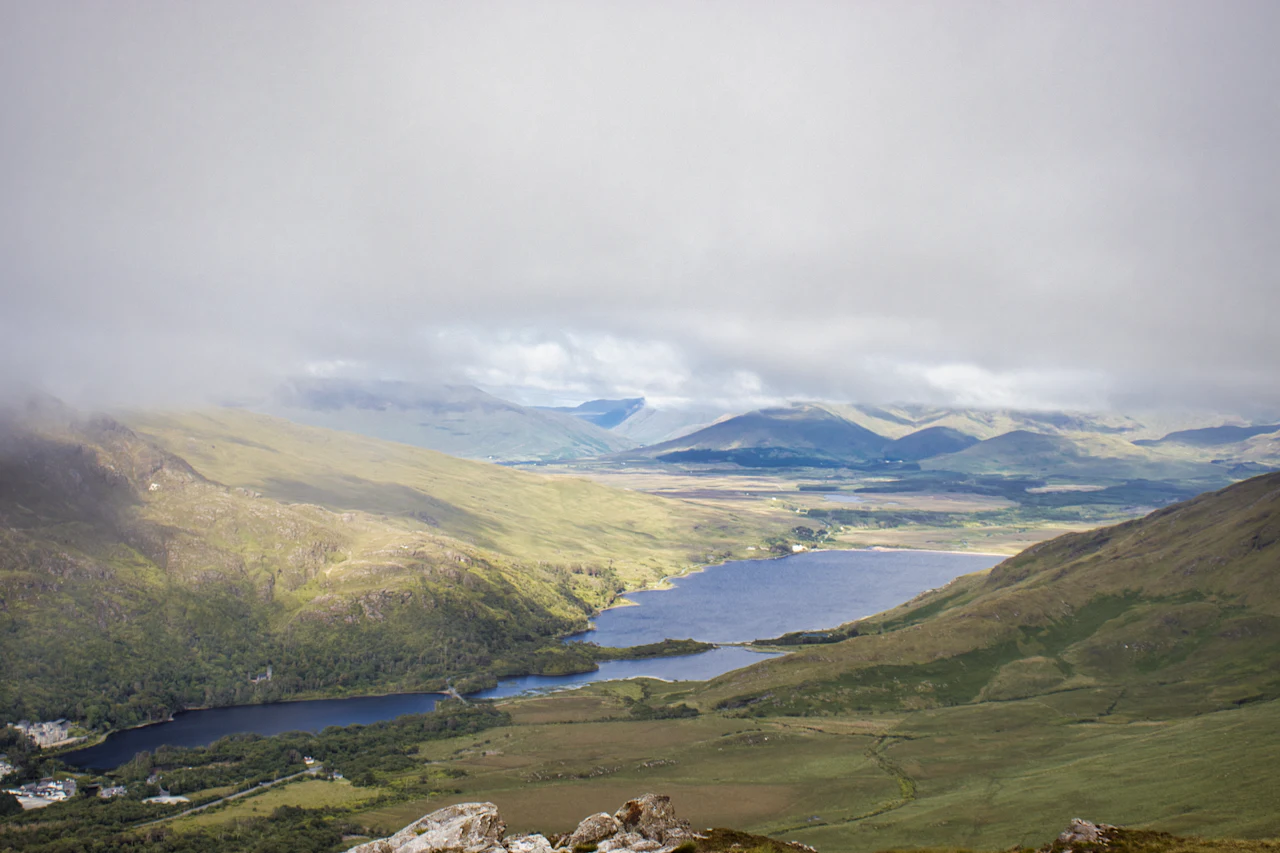 A lake lying between rolling green hills under a broad sky
