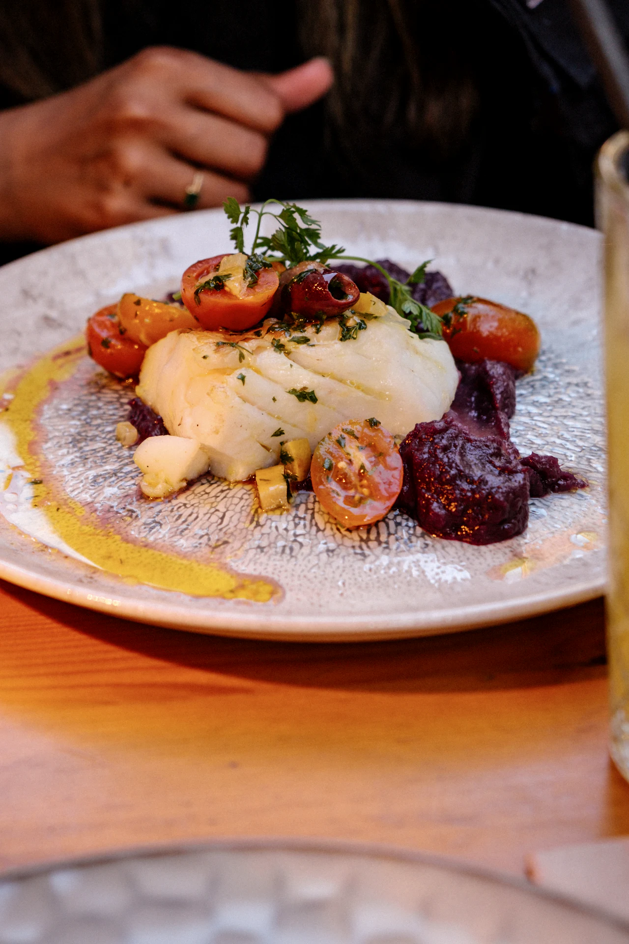 A fillet of white fish with roasted tomatoes and a golden sauce
