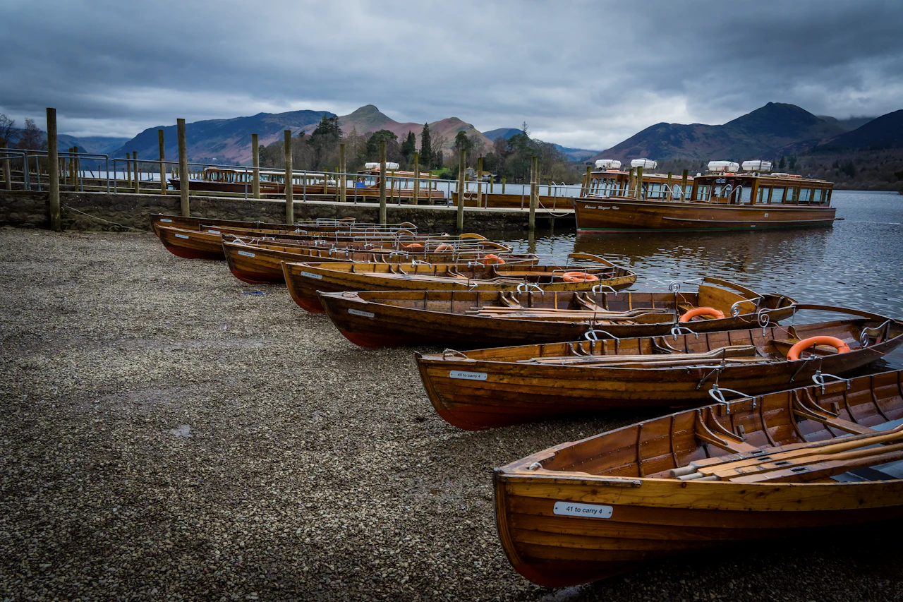 Rowing boats moored on a lake at dusk, with dark fells behind