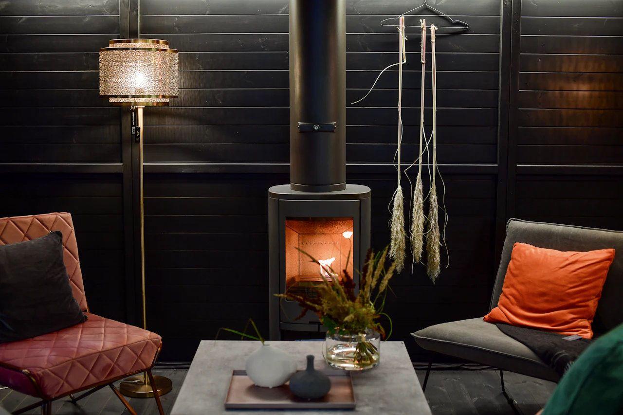 The House Suite sitting room, with a lit wood burner, armchairs and warm lamplight
