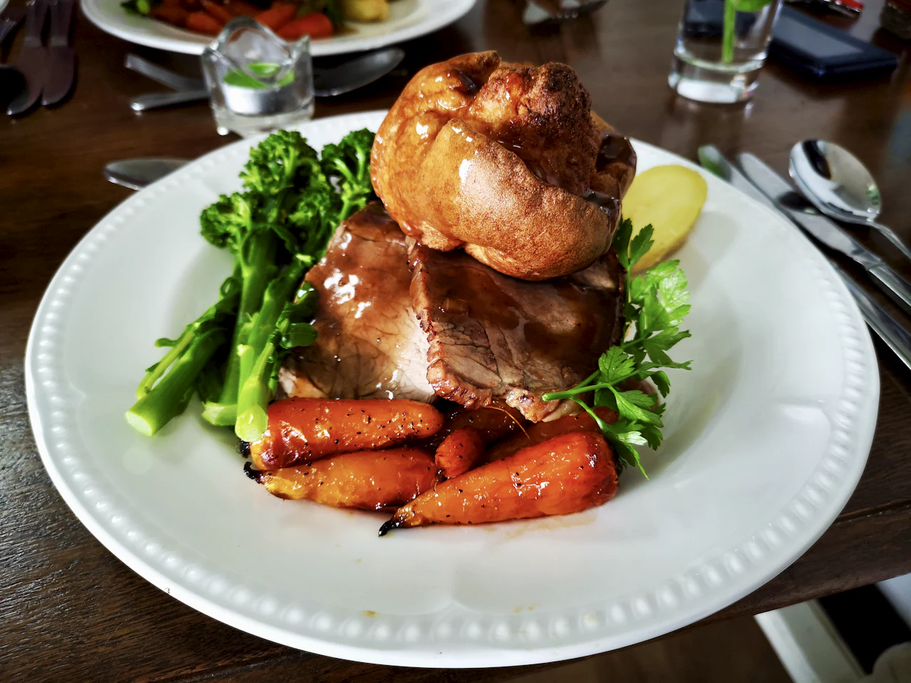 A plate of roast meat with greens and carrots